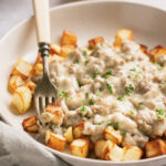 Keto and paleo sausage gravy over air fryer potatoes in a white bowl