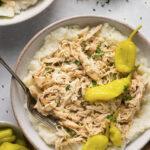 Mississippi chicken with pepperoncinis over mashed potatoes in a bowl