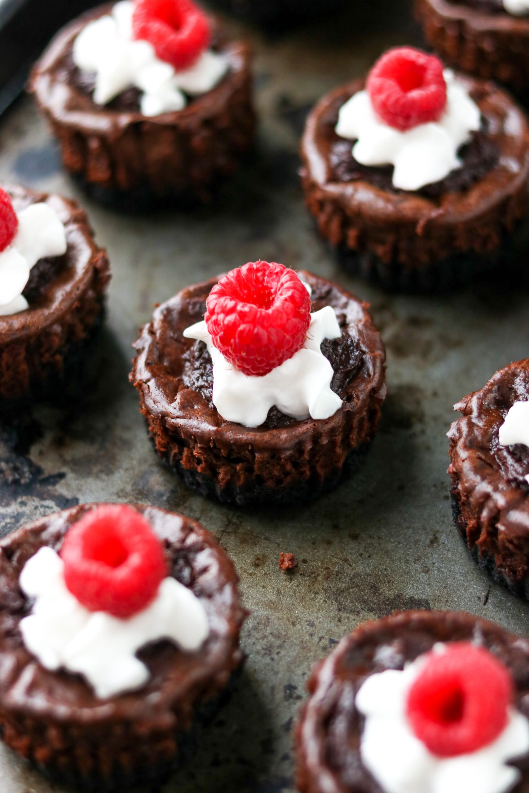 five mini protein cheesecakes topped with  whipped cream and a raspberry