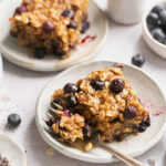 vegan baked oats on a plate with a gold fork taking a bite out
