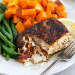 blackened mahi mahi on a plate with butternut squash and green beans with a fork flaking the fish apart