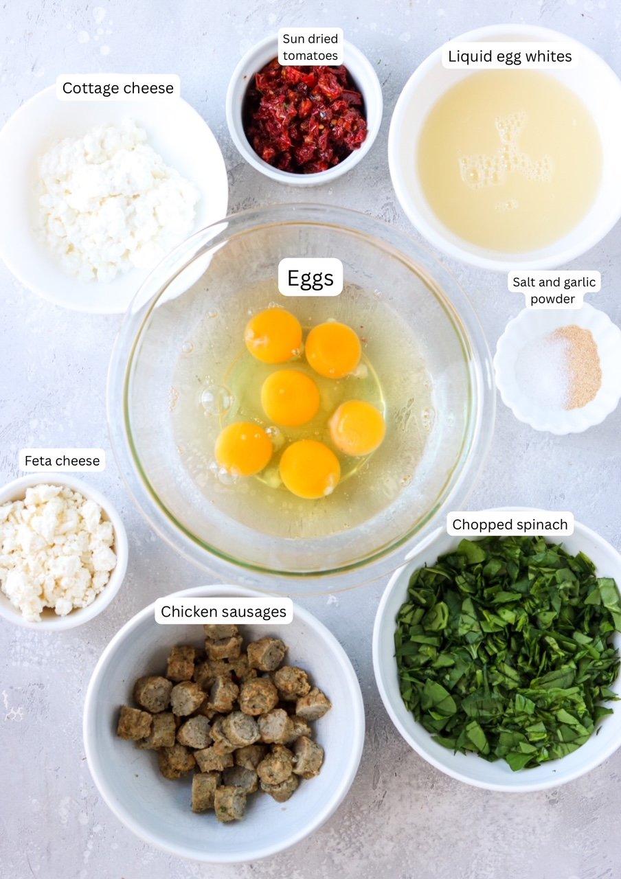 ingredients for spinach feta egg bites laid out on a photography backdrop in nesting bowls