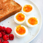 air fryer soft boiled eggs on a plate with toast and raspberries