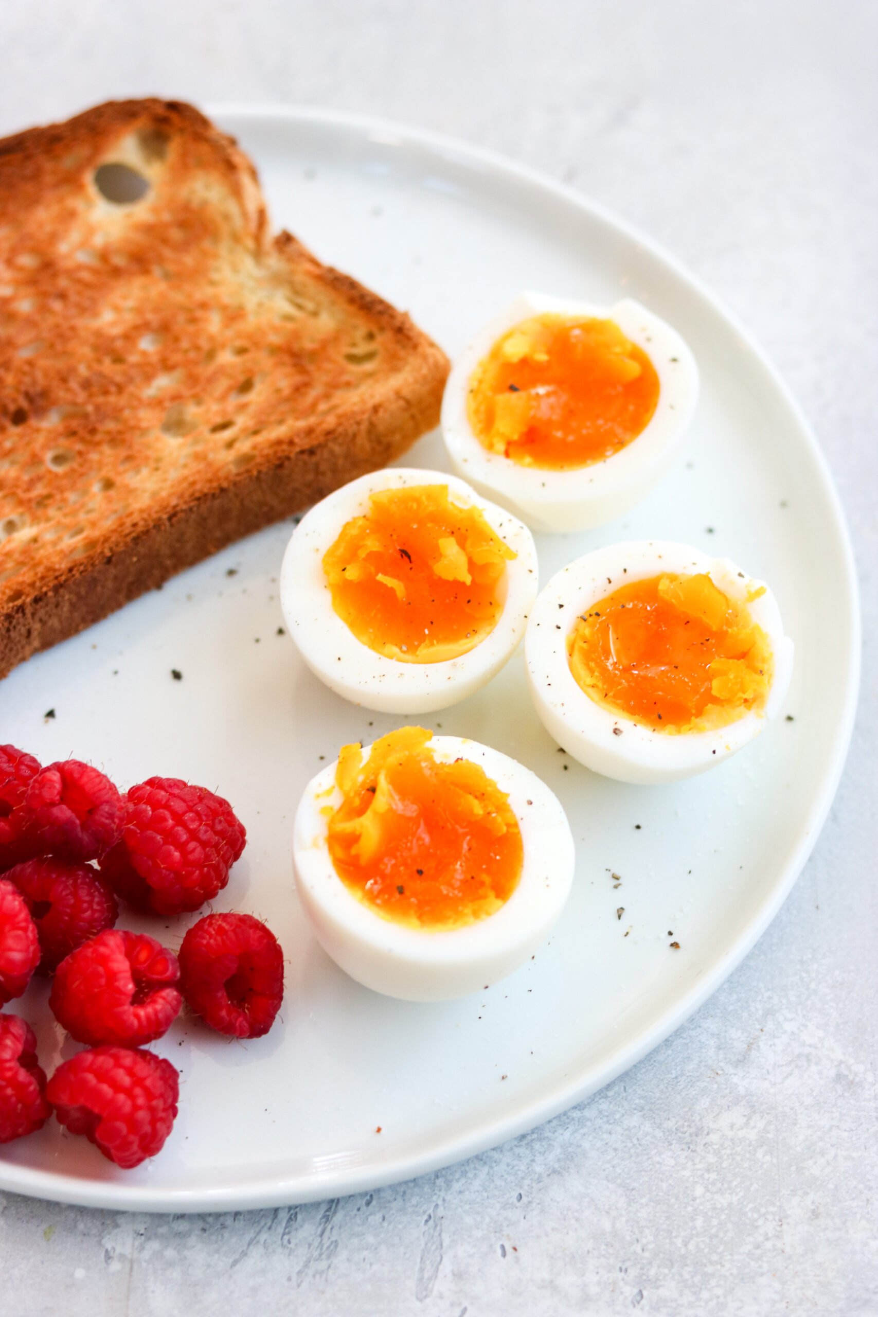 a white plate topped with eggs, toast, and raspberries. 