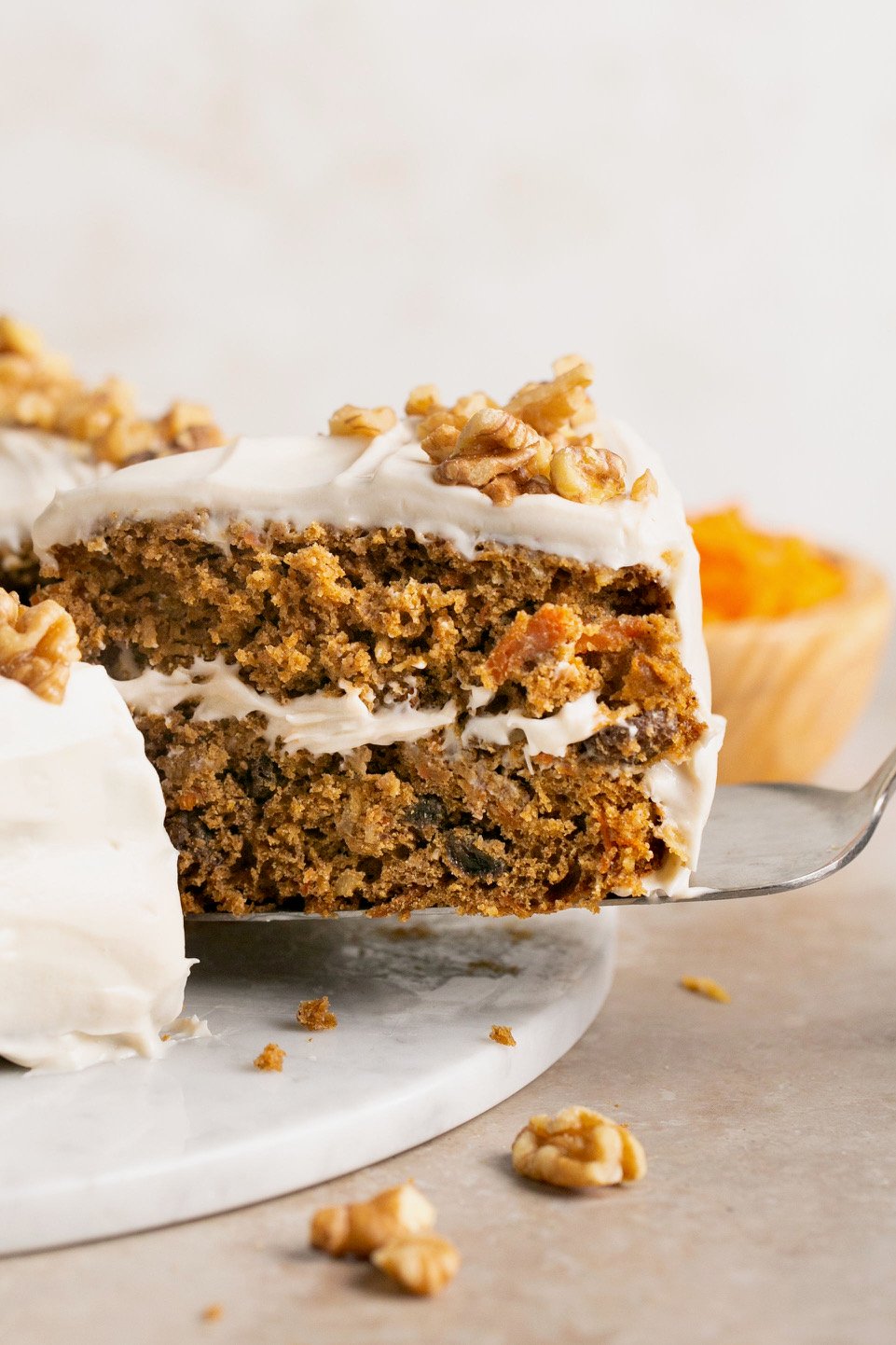 a slice of gluten free carrot cake being pulled out of the whole cake with a spatula