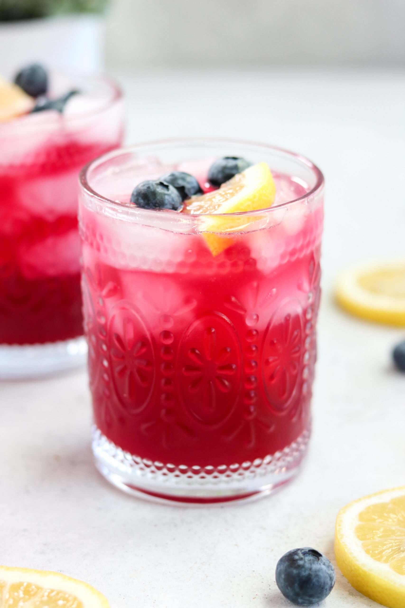 an up close photo of a mocktail topped with fresh blueberries and a slice of lemon. 
