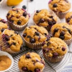 gluten free blueberry muffins on a cooling rack with a bowl of coconut sugar next to them