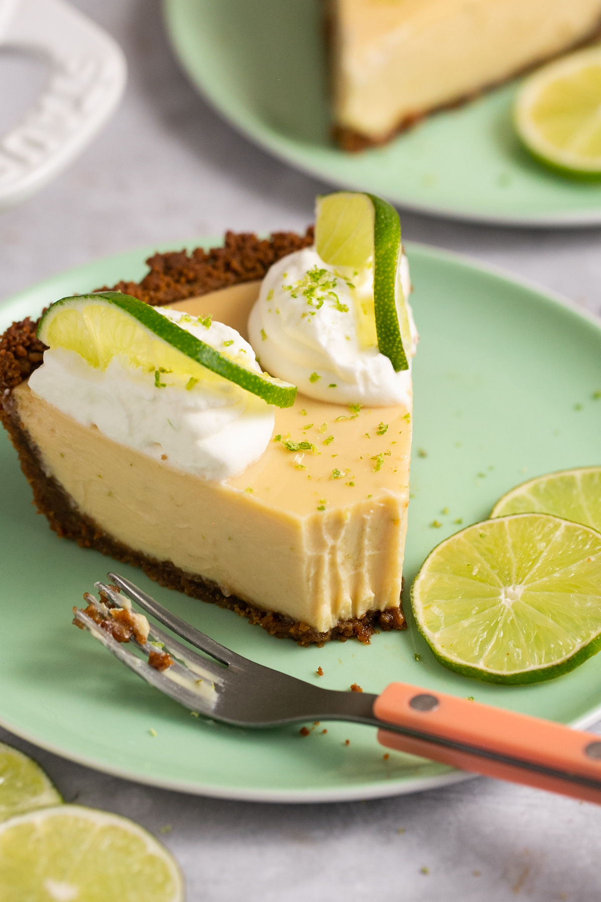 an up close shot of gluten-free key lime pie topped with whipped cream and lime wheels. 