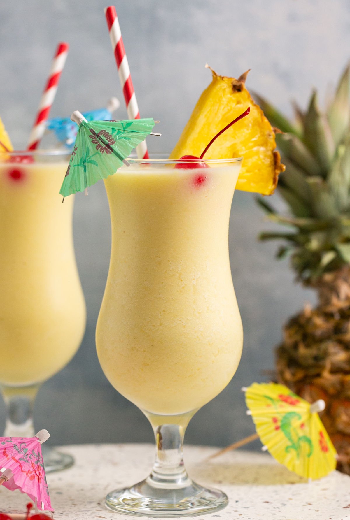 two piña colada mocktail drinks next to a pineapple.