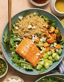 salmon quinoa bowl with brussels sprouts, sweet potatoes, arugula, apples and honey lime vinaigrette with a fork