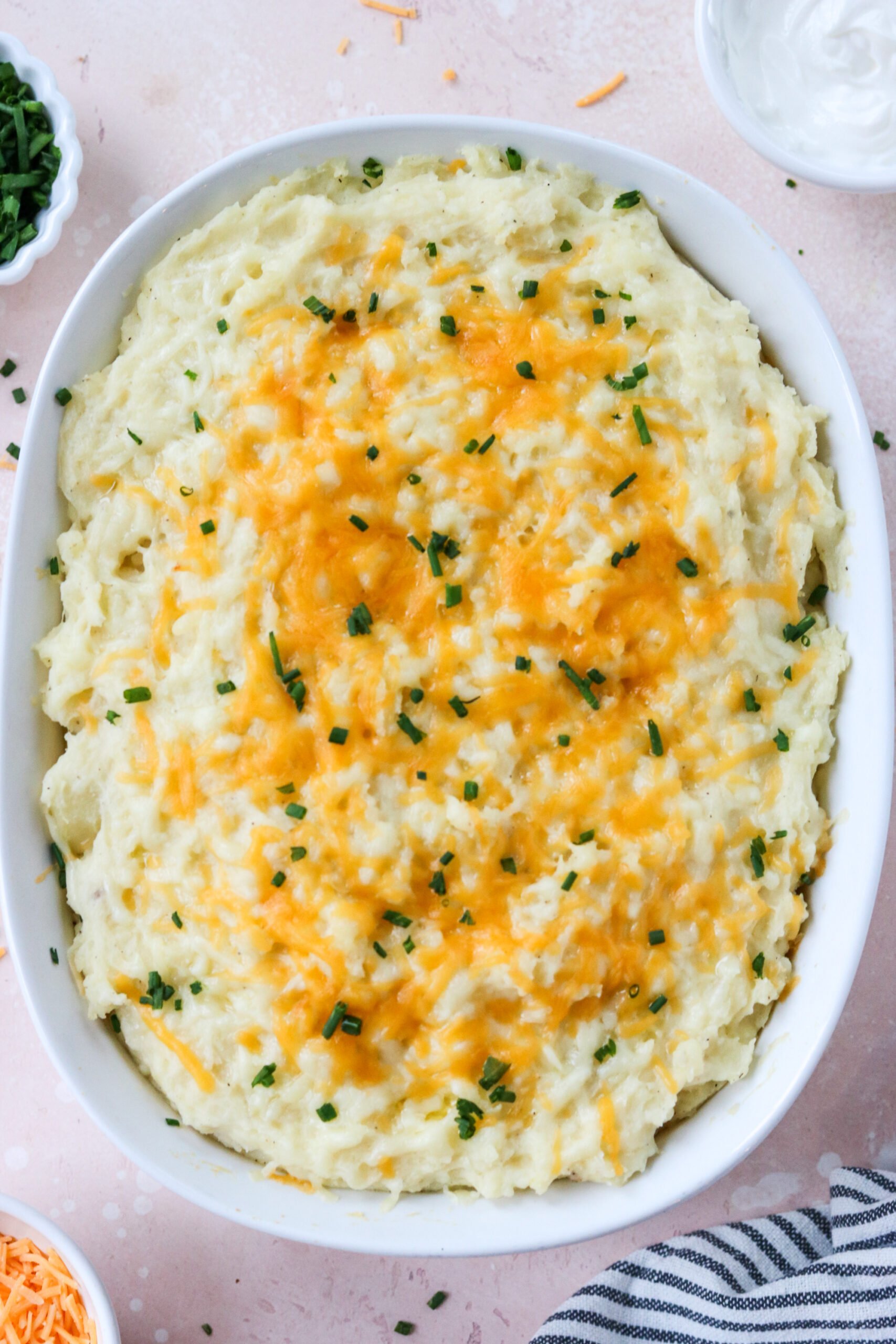 cheesy mashed potatoes in a casserole dish topped with chives