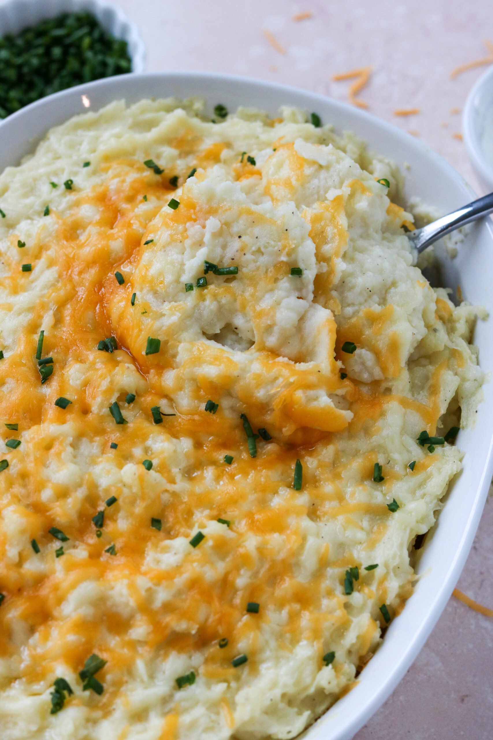 a spoon taking a scoop of cheesy mashed potatoes
