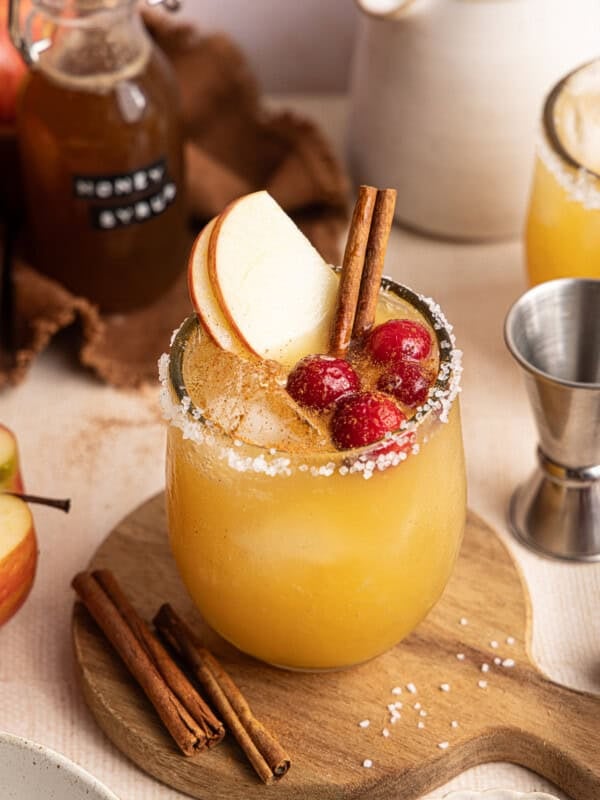 an apple cider margarita with apple slices and cranberries