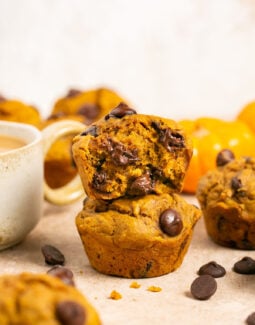 Pumpkin banana muffins with dark chocolate chips stacked one on top of the other with a bite taken out