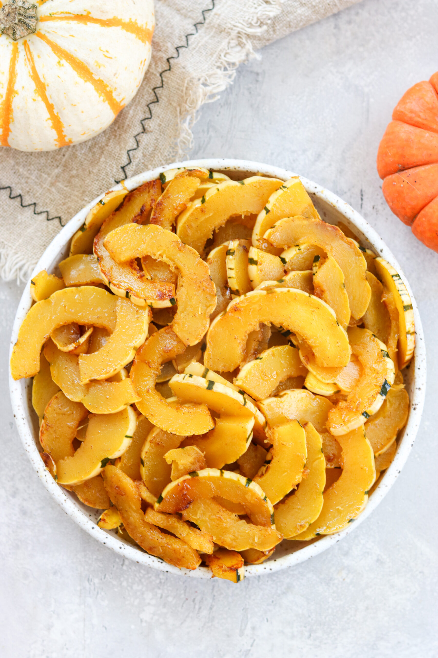 sauteed delicata squash in a bowl surrounded by pumpkins