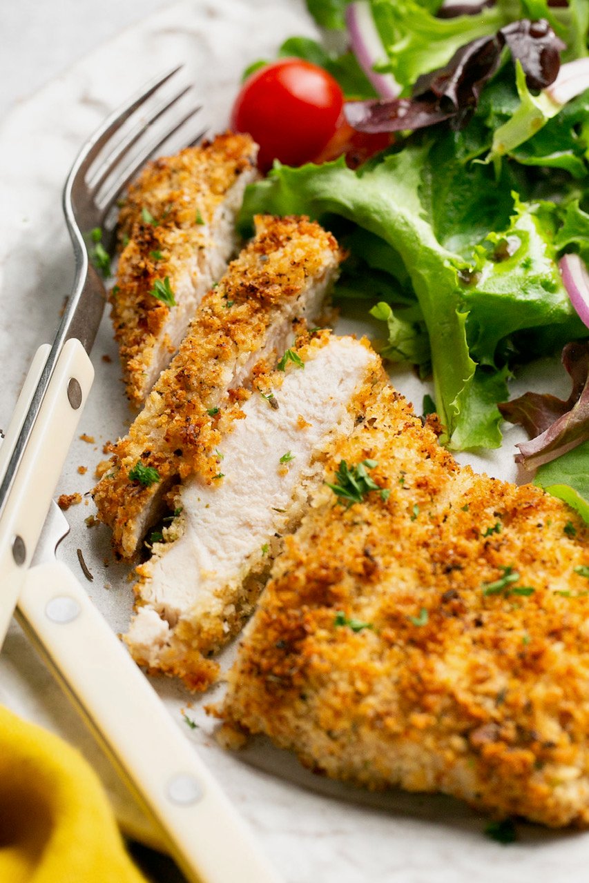 sliced air fryer chicken cutlet on a plate with salad