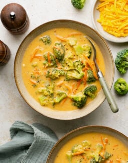 broccoli cheddar soup made in the instant pot in bowls with a spoon and a bowl of cheese on the side