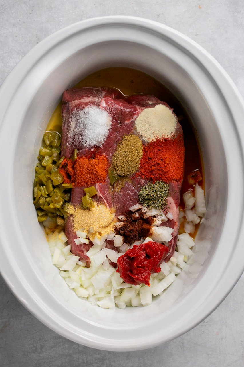 chuck roast with seasonings in a crock pot, uncooked