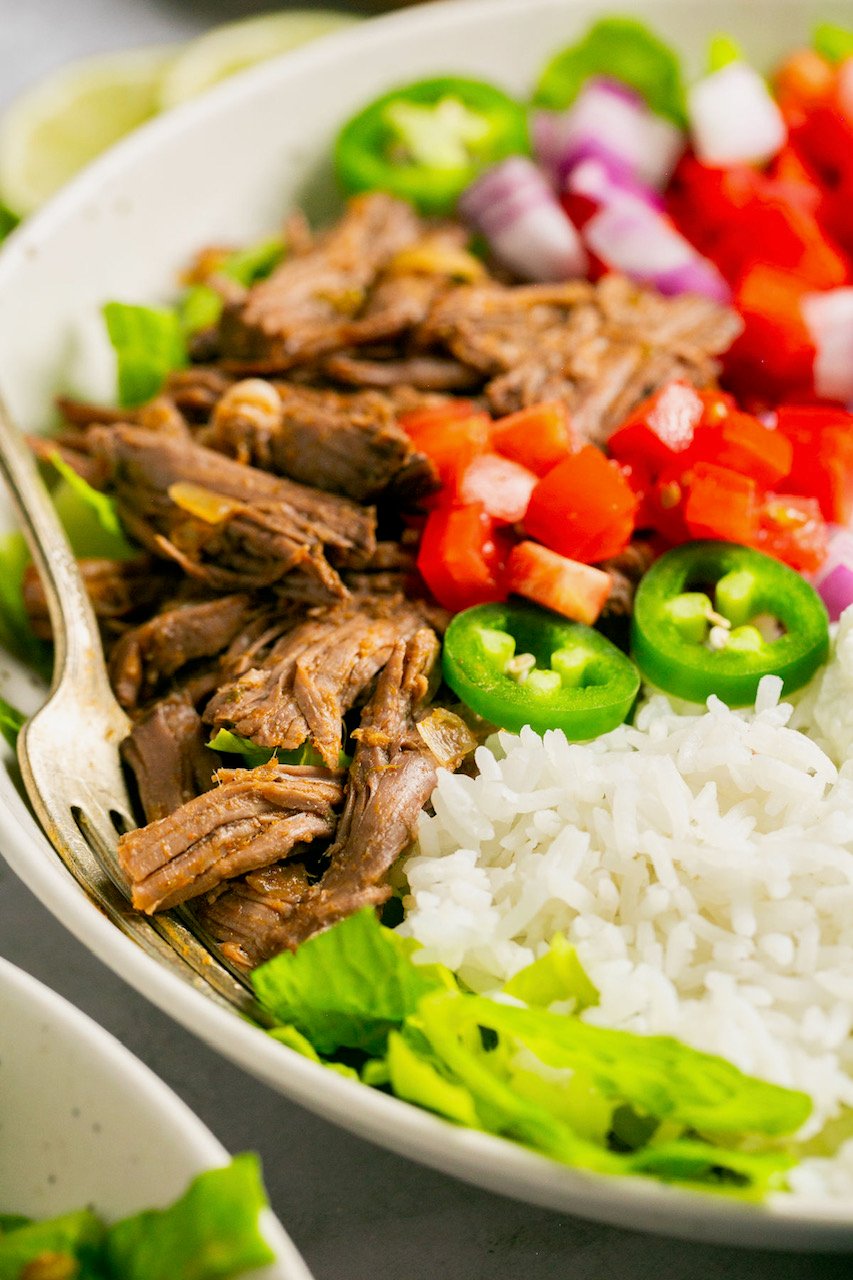 taco shredded beef in a bowl with rice and taco toppings