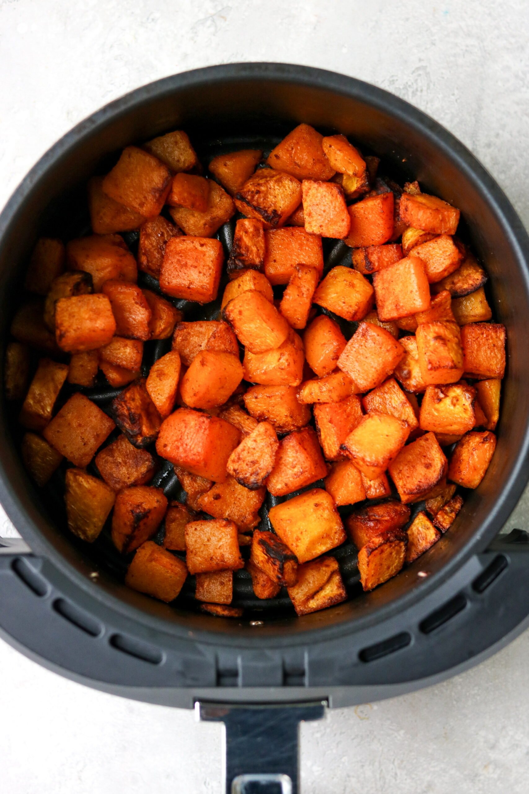 cooked butternut squash in an air fryer basket