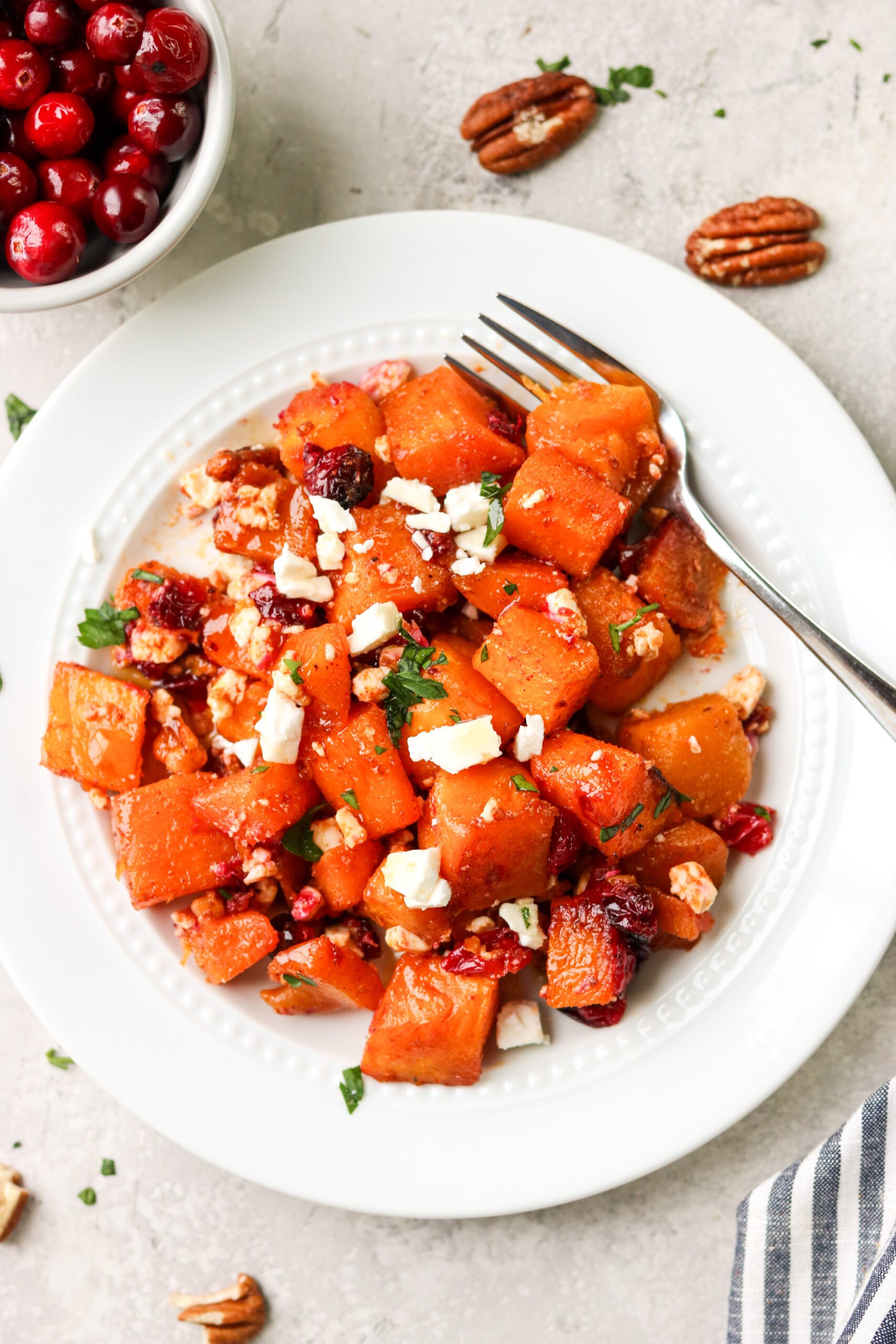 butternut squash with feta and cranberries on a plate with a fork 