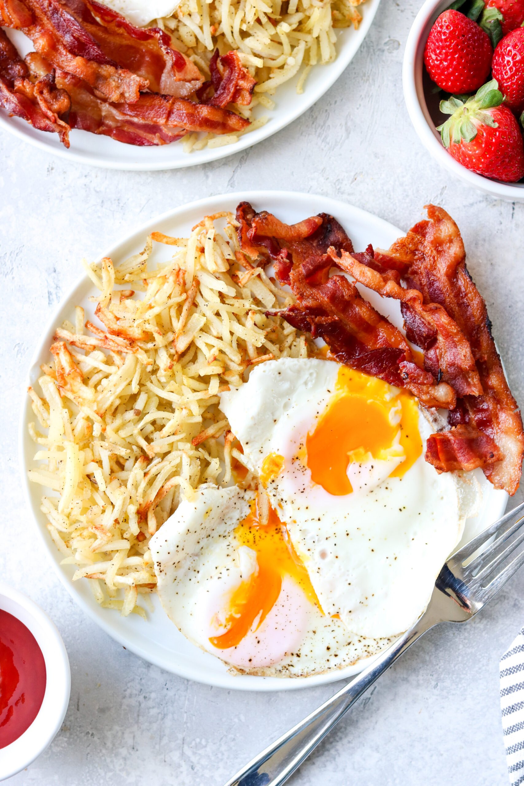 air fryer frozen hash browns on a plate with eggs and bacon