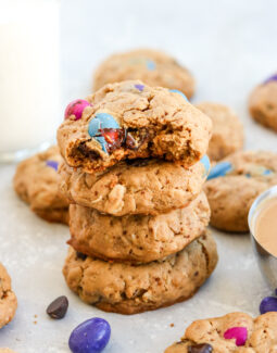 4 monster cookies stacked on top of each other surrounded by m&ms and other cookies