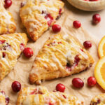 gluten free scones with orange and cranberry on a piece of parchment paper