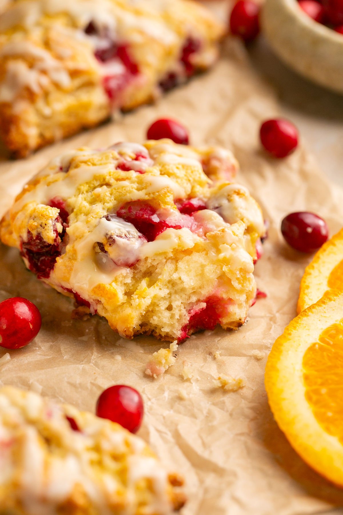 a cranberry orange gluten free scone on parchment paper with a bite taken out