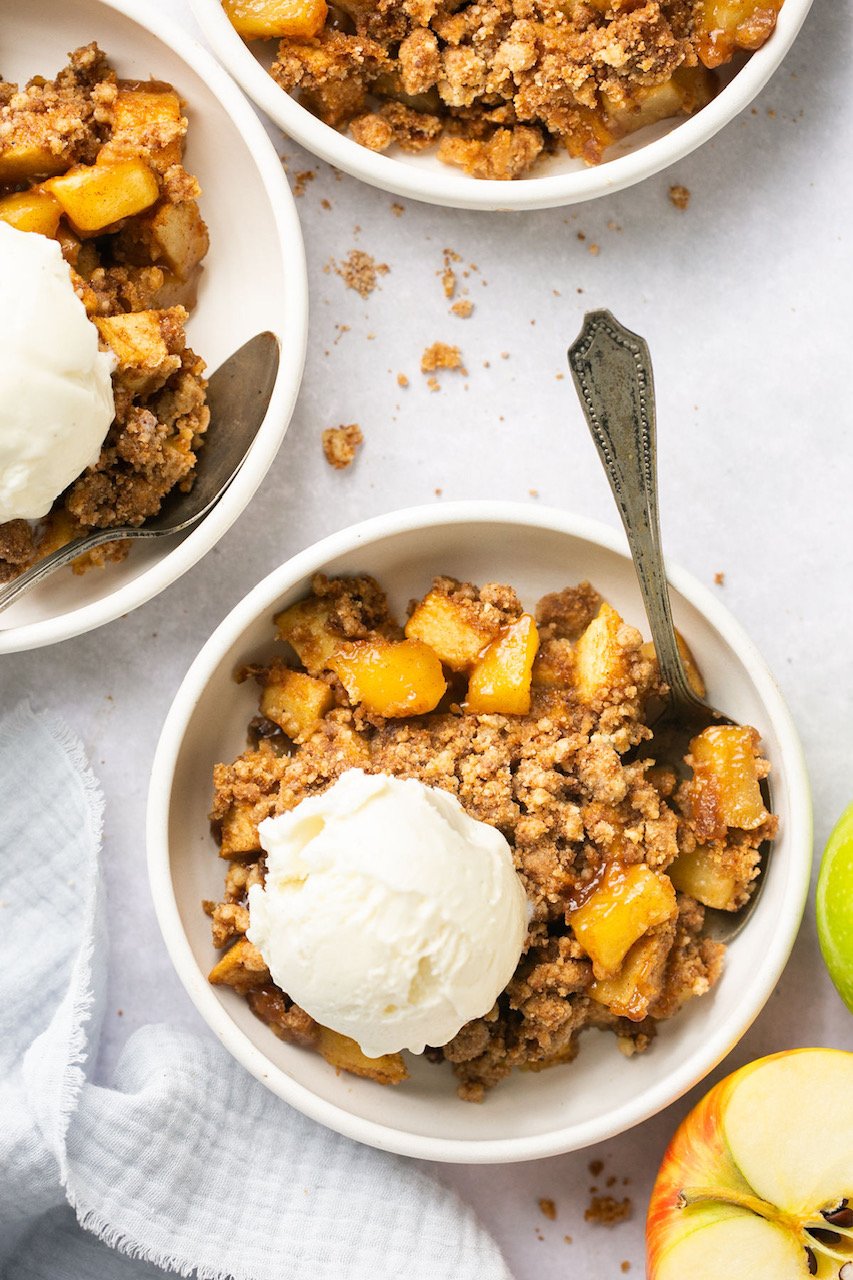 healthy apple crumble in a bowl topped with vanilla ice cream