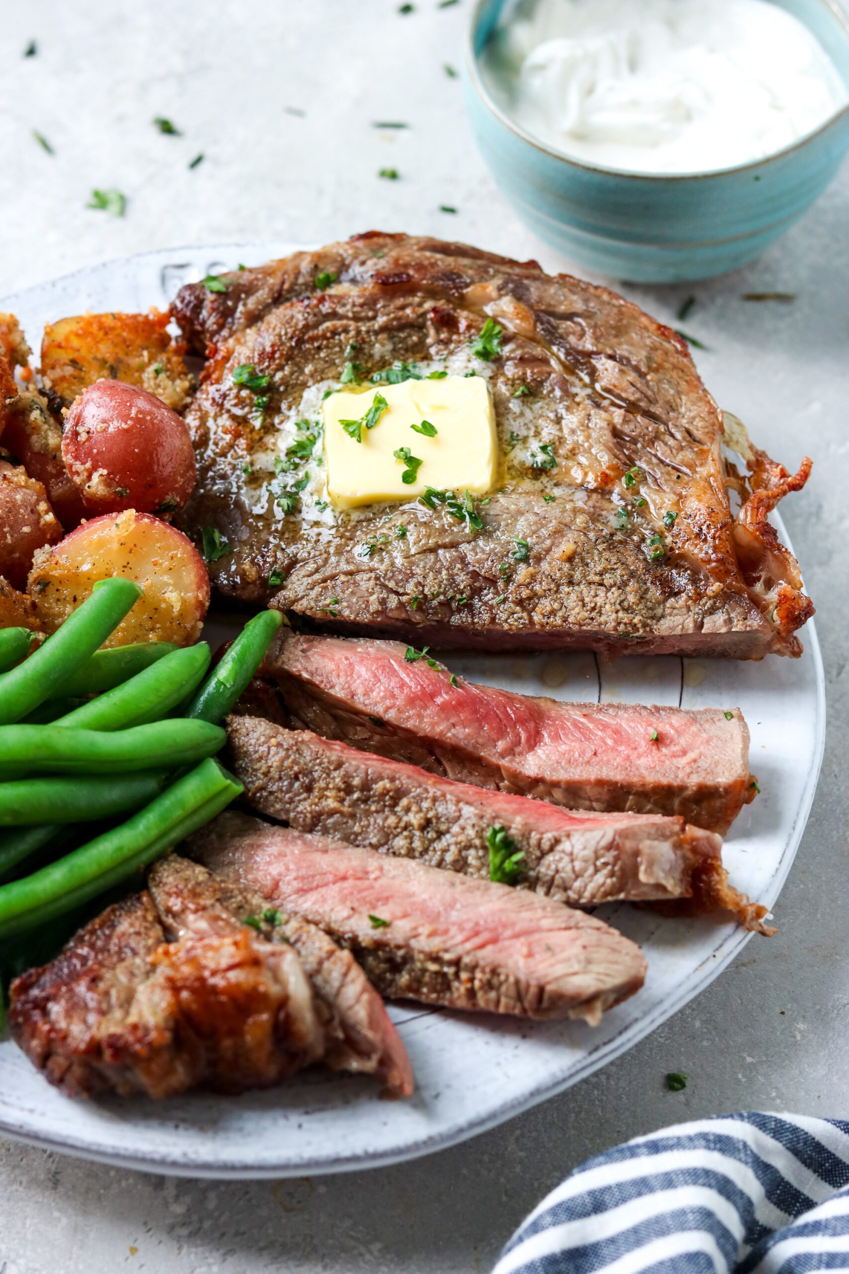 ribeye steak on a plate with green beans and potatoes