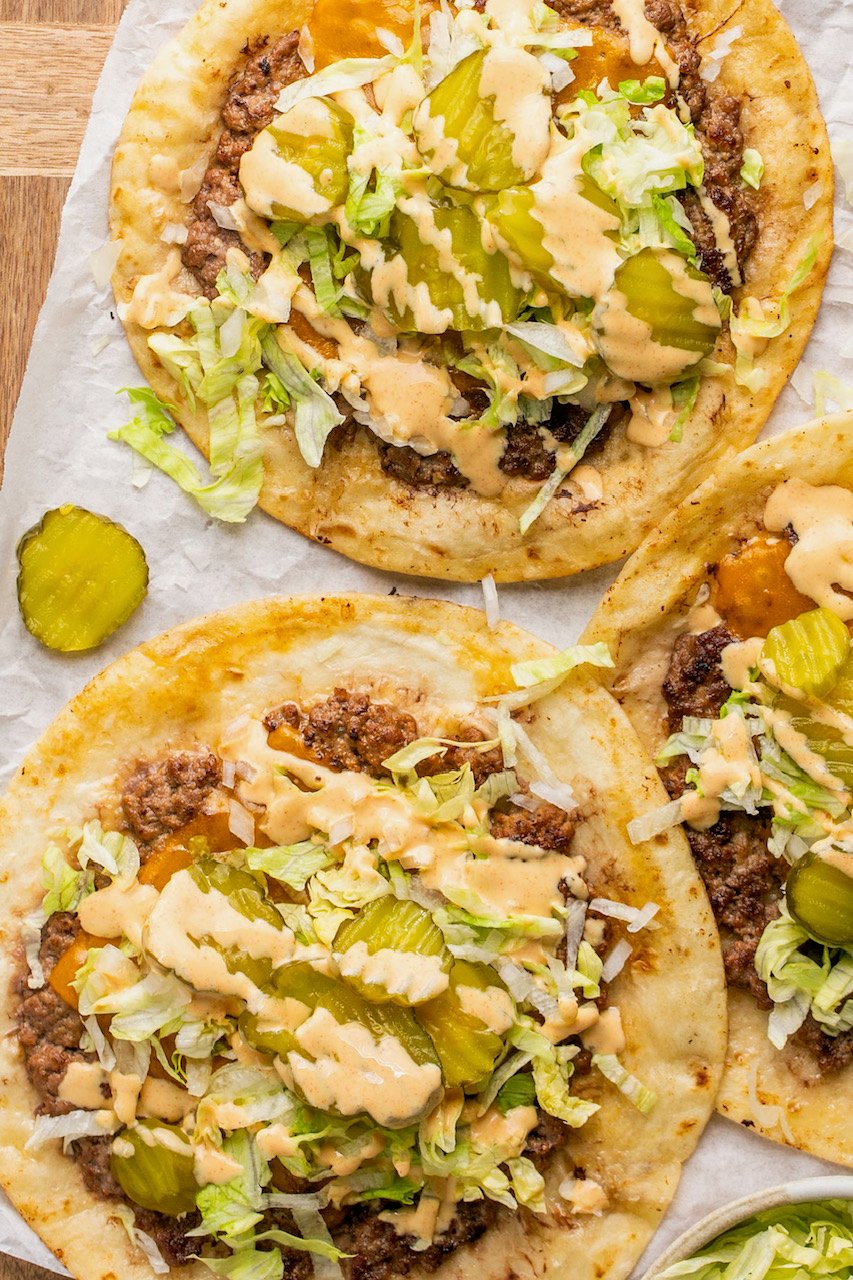 big mac tacos with toppings and sauce on parchment paper