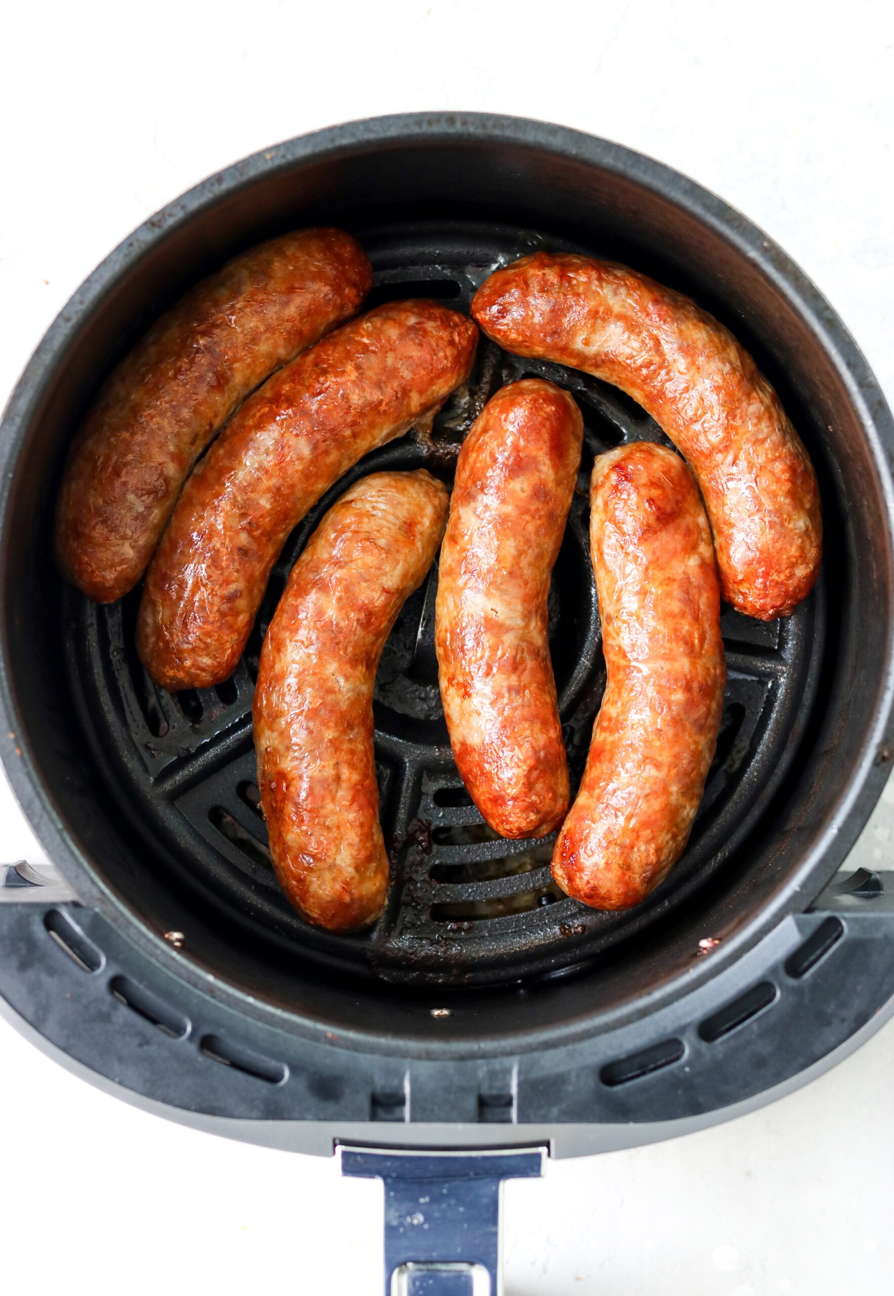 cooked Italian sausages in an air fryer basket