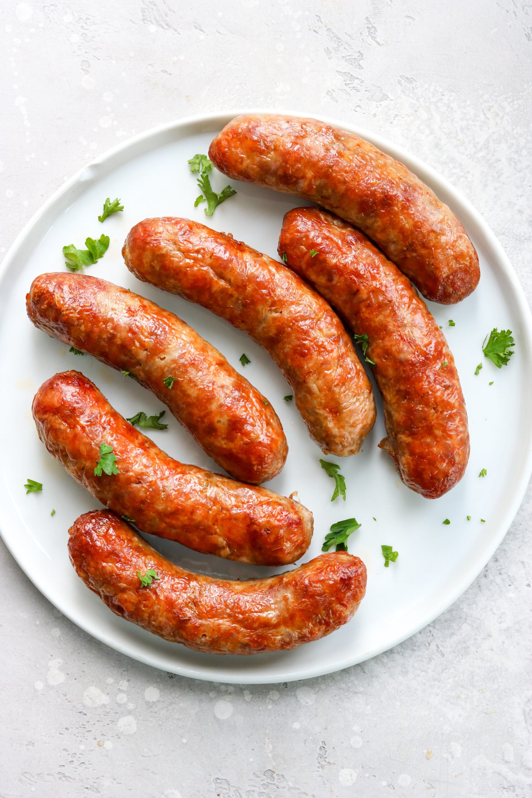air fried Italian sausage on a white plate topped with parsley