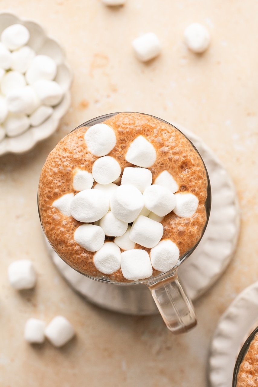 an overhead shot of bone broth hot chocolate in a glass mug topped with marshmallows 