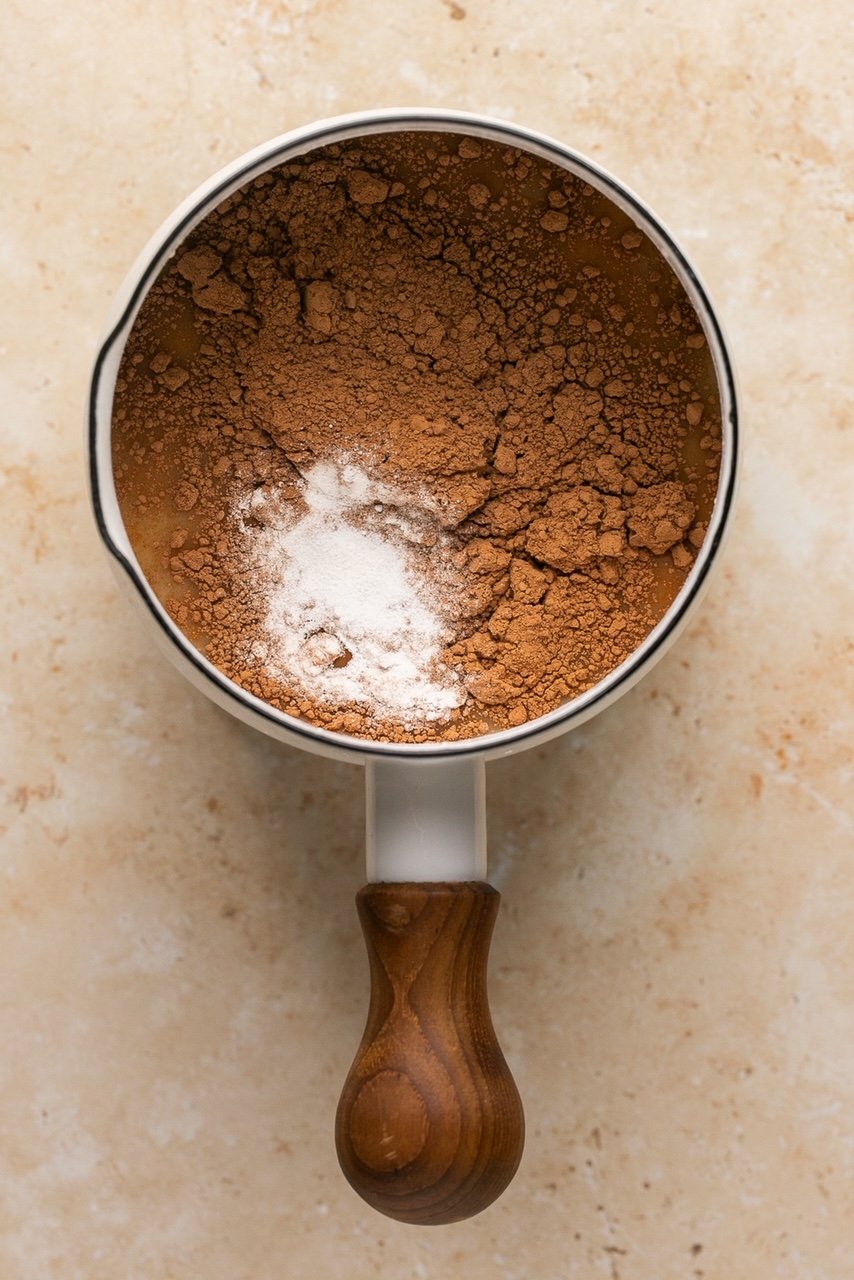 a small sauce pan with collagen, broth, cocoa powder, and maple syrup in it