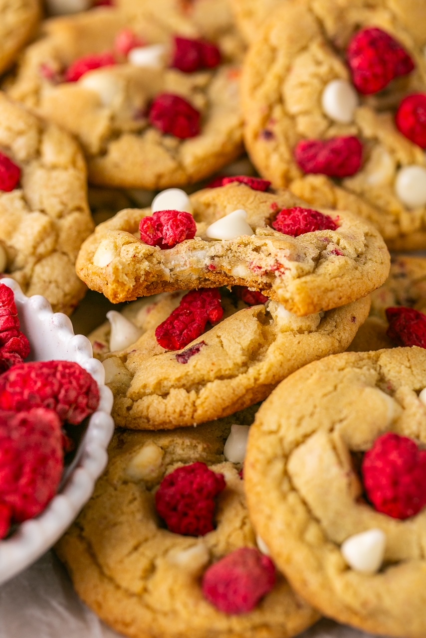 white chocolate raspberry cookies in a pile with a bite taken out of one