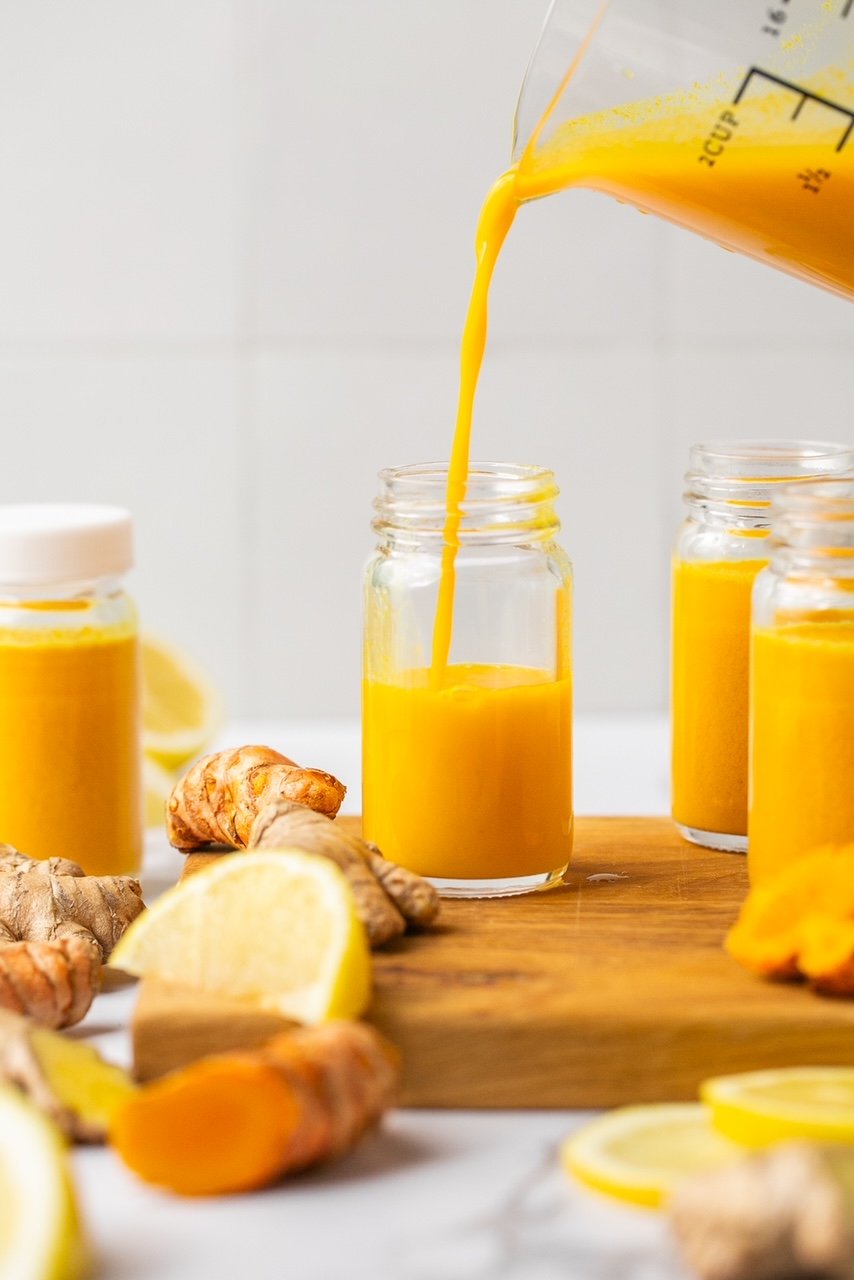 lemon ginger turmeric juice being poured into a mini glass bottle