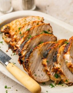 air fryer pork roast sliced on a white platter with a knife
