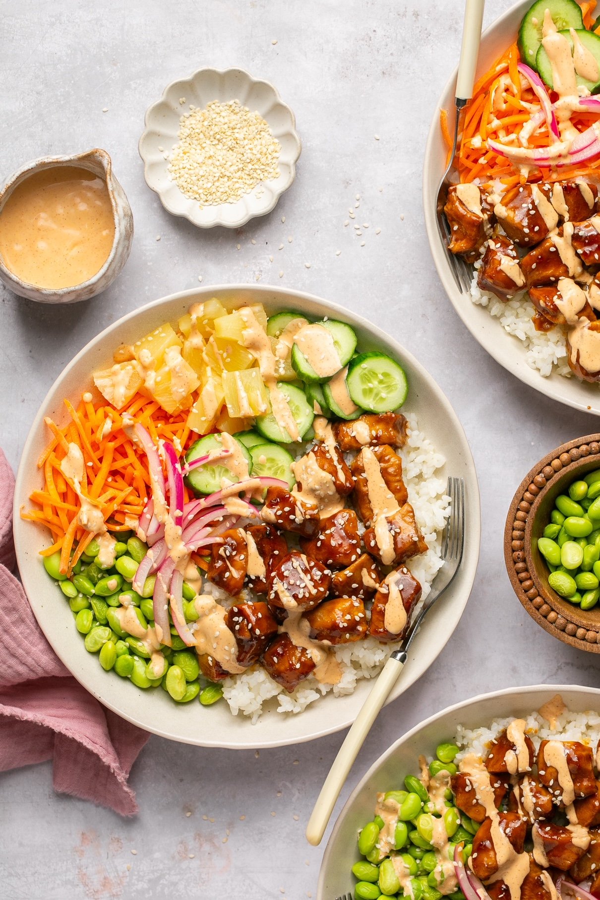chicken poke bowls with toppings surrounded by small bowls of garnishes