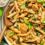 Marry me chicken pasta in a skillet with a wooden spoon