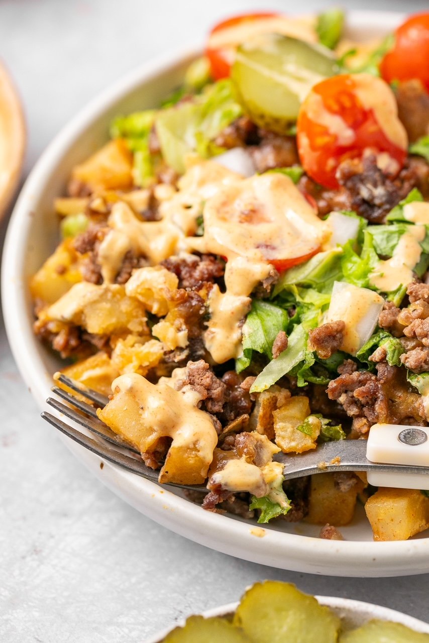 a close-up of ground beef and potatoes with sauce in a bowl with lettuce and tomato