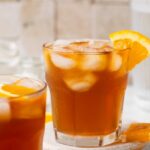 espresso tonic in a glass garnished with an orange
