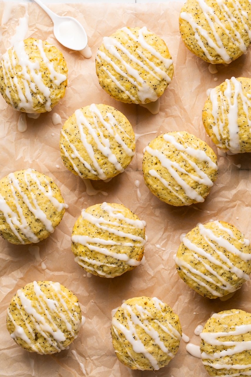 lemon poppy seed muffins on a piece of parchment paper drizzled with glaze