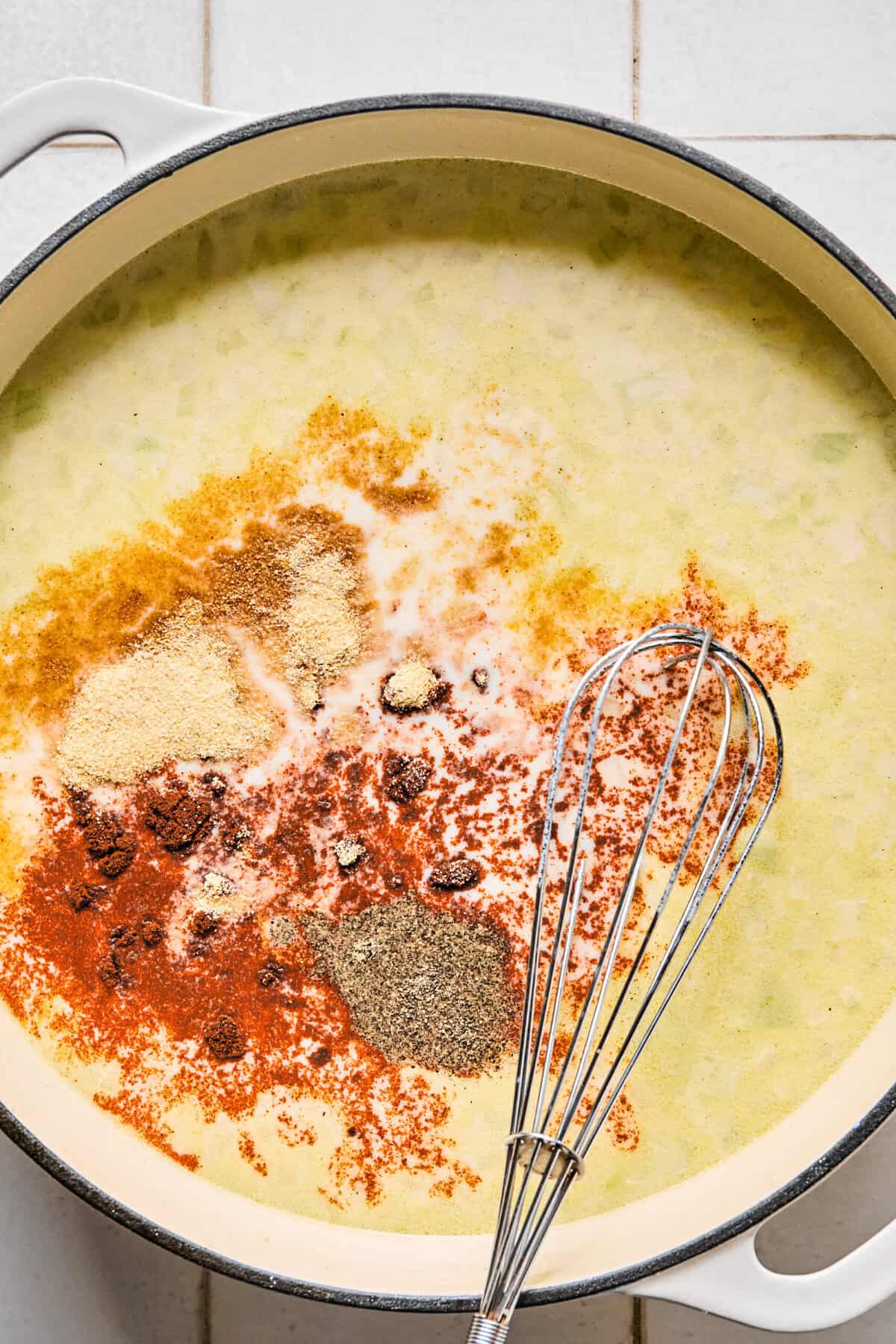 Seasonings in the pan of milk, broth, flour, and sautéed onions and garlic.