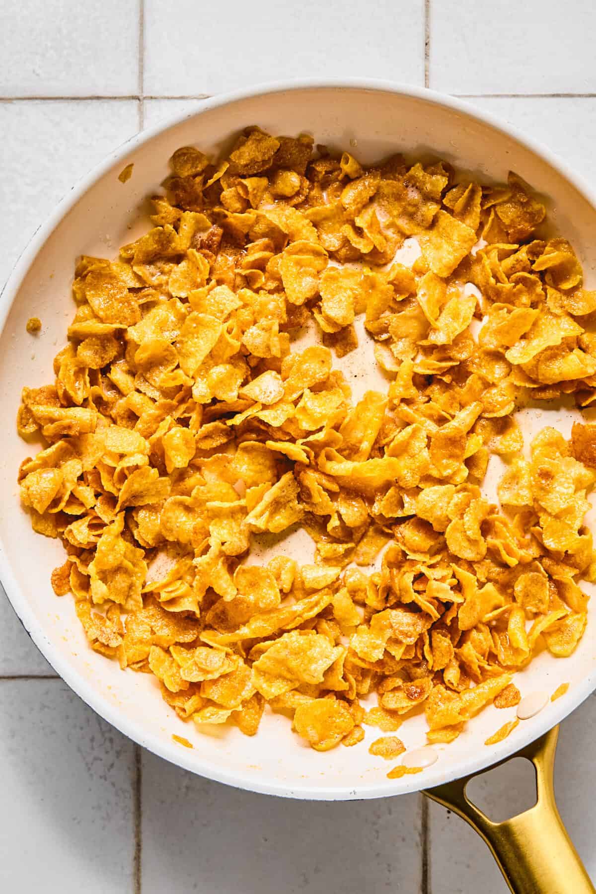 Gluten-free cornflakes being toasted in a large pan.