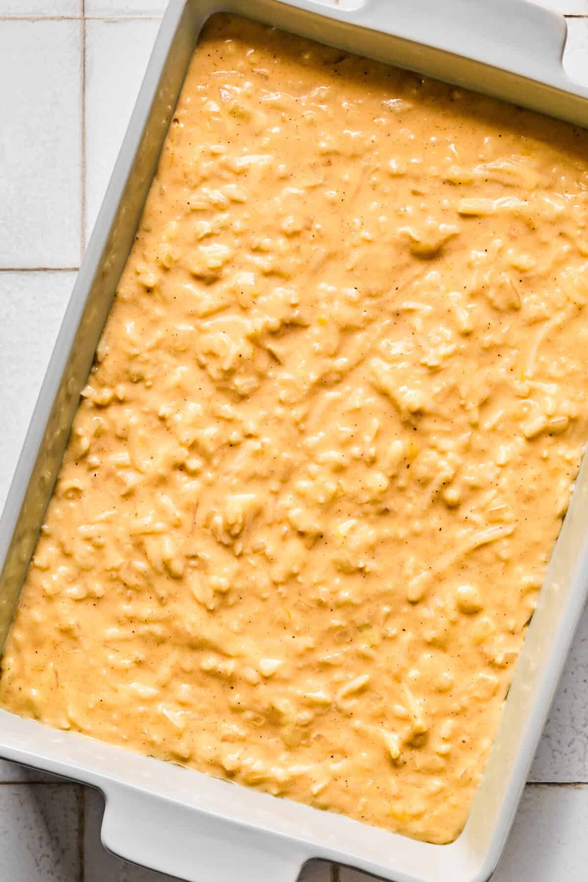 Cheesy hashbrown casserole mixture in a baking dish.