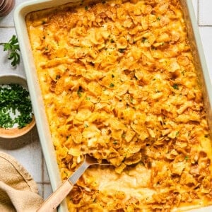cheesy hashbrown casserole in a dish with a spoon taking a scoop