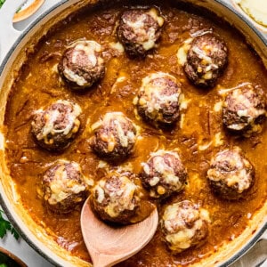french onion meatballs in a skillet with a wooden spoon