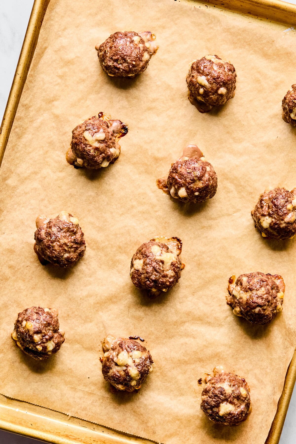 Formed meatballs on a parchment-lined baking sheet.